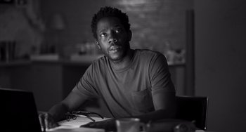 Movie still from “Paris, 13th District” (2021), directed by Jacques Audiard – A man sitting at a table with a pen in his hand; Close Up shot, Low angle