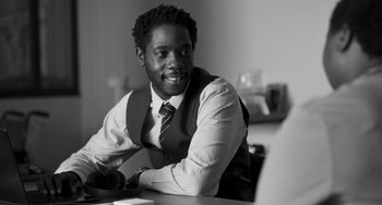 Movie still from “Paris, 13th District” (2021), directed by Jacques Audiard – A man sitting at a table in front of a computer; Close Up shot, Over the shoulder angle