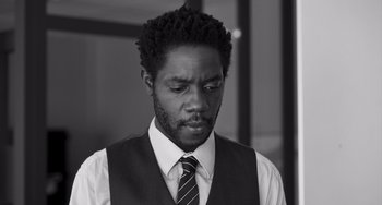 Movie still from “Paris, 13th District” (2021), directed by Jacques Audiard – A black and white photo of a man in a vest and tie; Close Up shot, Low angle