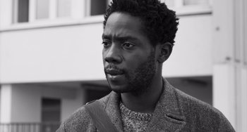 Movie still from “Paris, 13th District” (2021), directed by Jacques Audiard – A black and white photo of a man with a beard; Close Up shot, Low angle