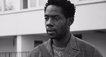 Movie still from “Paris, 13th District” (2021), directed by Jacques Audiard – A black and white photo of a man in a jacket; Close Up shot, Low angle