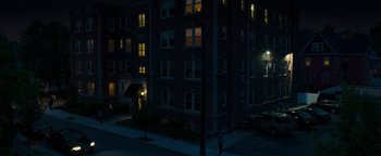 Movie still from “Patriots Day” (2016), directed by Peter Berg – A person standing on the sidewalk in front of an apartment building; Extreme Wide shot, High angle