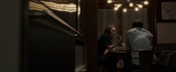 Movie still from “Patriots Day” (2016), directed by Peter Berg – A woman sitting at a table eating food; Medium shot, Over the shoulder angle