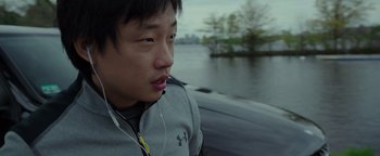 Movie still from “Patriots Day” (2016), directed by Peter Berg – A young man wearing headphones and looking at the camera; Close Up shot, Over the shoulder angle