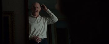 Movie still from “Patriots Day” (2016), directed by Peter Berg – A bald man in a white dress shirt is holding a cell phone; Close Up shot, Over the shoulder angle