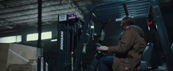 Movie still from “Patriots Day” (2016), directed by Peter Berg – A man sitting on top of a forklift in a warehouse; Medium shot, Low angle