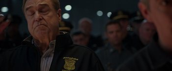 Movie still from “Patriots Day” (2016), directed by Peter Berg – A man in a police uniform standing in front of a group of people; Close Up shot, Over the shoulder angle