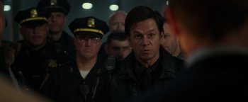 Movie still from “Patriots Day” (2016), directed by Peter Berg – A group of men standing next to each other in a room; Close Up shot, Over the shoulder angle