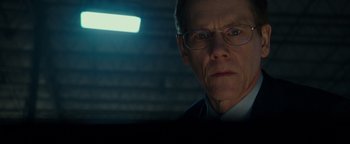Movie still from “Patriots Day” (2016), directed by Peter Berg – A person wearing a suit and glasses; Close Up shot, Over the shoulder angle