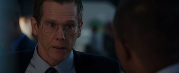 Movie still from “Patriots Day” (2016), directed by Peter Berg – A person wearing a suit and glasses; Close Up shot, Over the shoulder angle