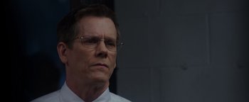 Movie still from “Patriots Day” (2016), directed by Peter Berg – A person wearing glasses and a white shirt; Close Up shot, Over the shoulder angle