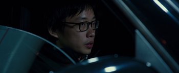 Movie still from “Patriots Day” (2016), directed by Peter Berg – A man with glasses sitting in the driver's seat of a car; Close Up shot, Over the shoulder angle
