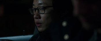 Movie still from “Patriots Day” (2016), directed by Peter Berg – A man wearing glasses and a black jacket; Close Up shot, Over the shoulder angle