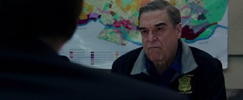 Movie still from “Patriots Day” (2016), directed by Peter Berg – An older man is sitting in front of a map; Close Up shot, Over the shoulder angle