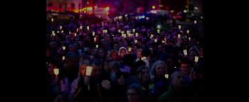 Movie still from “Patriots Day” (2016), directed by Peter Berg – A large crowd of people are holding candles in their hands; Extreme Wide shot, High angle