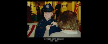 Movie still from “Patriots Day” (2016), directed by Peter Berg – A police officer in uniform is pinning a badge on a woman's lapel; Medium shot, Overhead angle