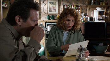 Movie still from “The Bridges of Madison County” (1995), directed by Clint Eastwood – A woman sitting at a table looking at a paper; Medium shot, Over the shoulder angle