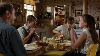 Movie still from “The Bridges of Madison County” (1995), directed by Clint Eastwood – A group of people sitting at a table with plates of food; Medium shot, Over the shoulder angle