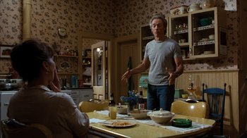 Movie still from “The Bridges of Madison County” (1995), directed by Clint Eastwood – A man standing in front of a table in a kitchen; Medium shot, Over the shoulder angle