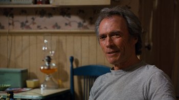 Movie still from “The Bridges of Madison County” (1995), directed by Clint Eastwood – A person sitting in a chair near a table; Close Up shot, Over the shoulder angle
