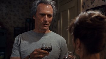 Movie still from “The Bridges of Madison County” (1995), directed by Clint Eastwood – A man holding a glass of red wine in front of a woman; Close Up shot, Over the shoulder angle