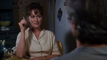 Movie still from “The Bridges of Madison County” (1995), directed by Clint Eastwood – A woman sitting in front of a man holding a cell phone; Close Up shot, Over the shoulder angle