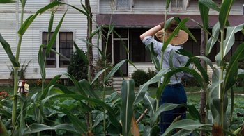 Movie still from “The Bridges of Madison County” (1995), directed by Clint Eastwood – A woman standing in a garden with a straw hat on; Wide shot, Low angle