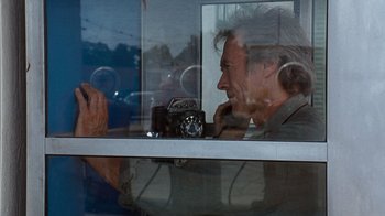 Movie still from “The Bridges of Madison County” (1995), directed by Clint Eastwood – A man sitting in front of a window with an old camera; Medium shot, Over the shoulder angle