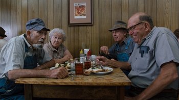 Movie still from “The Bridges of Madison County” (1995), directed by Clint Eastwood – A group of people sitting at a table with plates of food; Medium shot, Over the shoulder angle