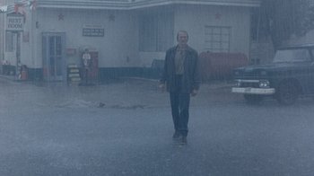 Movie still from “The Bridges of Madison County” (1995), directed by Clint Eastwood – A man walking in the middle of a street in the rain; Wide shot, Low angle