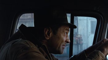 Movie still from “The Bridges of Madison County” (1995), directed by Clint Eastwood – A man wearing a hat looking out a window; Close Up shot, Over the shoulder angle