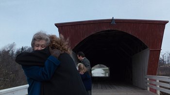 Movie still from “The Bridges of Madison County” (1995), directed by Clint Eastwood – Two people hug in front of a covered bridge; Wide shot, Over the shoulder angle