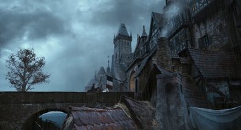 Movie still from “The Brothers Grimm” (2005), directed by Terry Gilliam – A group of people standing on a bridge near a building; Extreme Wide shot, Low angle