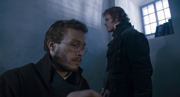 Movie still from “The Brothers Grimm” (2005), directed by Terry Gilliam – Two men are standing side by side in the dark; Close Up shot, Over the shoulder angle