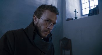 Movie still from “The Brothers Grimm” (2005), directed by Terry Gilliam – A man wearing glasses and a black jacket; Close Up shot, Low angle