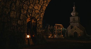 Movie still from “The Brothers Grimm” (2005), directed by Terry Gilliam – A man standing in front of a stone wall at night; Wide shot, Low angle