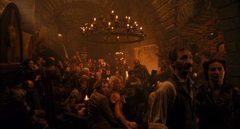 Movie still from “The Brothers Grimm” (2005), directed by Terry Gilliam – A group of people sitting in a room with candles on the ceiling; Wide shot, High angle
