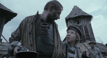 Movie still from “The Brothers Grimm” (2005), directed by Terry Gilliam – A man standing next to a young girl in front of a building; Medium shot, Low angle