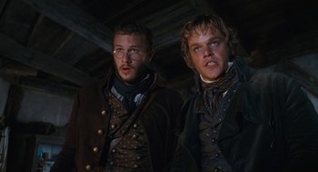 Movie still from “The Brothers Grimm” (2005), directed by Terry Gilliam – A couple of men standing next to each other; Medium shot, Low angle
