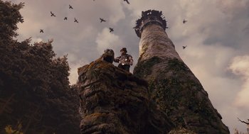 Movie still from “The Brothers Grimm” (2005), directed by Terry Gilliam – A man standing on top of a rock near a tower; Extreme Wide shot, Low angle