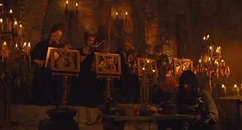Movie still from “The Brothers Grimm” (2005), directed by Terry Gilliam – A group of people in a room playing music; Wide shot, Low angle