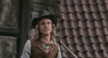 Movie still from “The Brothers Grimm” (2005), directed by Terry Gilliam – A man in a hat and vest standing in front of a building; Close Up shot, Low angle
