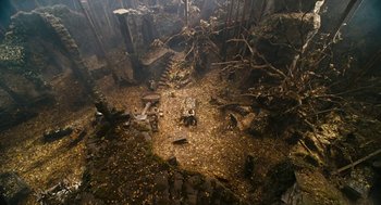 Movie still from “The Brothers Grimm” (2005), directed by Terry Gilliam – An aerial view of a forest with trees and rocks; Extreme Wide shot, High angle