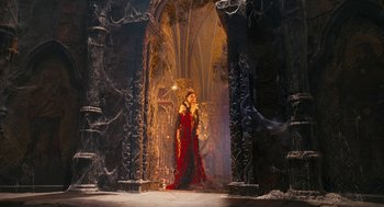 Movie still from “The Brothers Grimm” (2005), directed by Terry Gilliam – A woman dressed in a red dress standing in front of a throne; Wide shot, Low angle