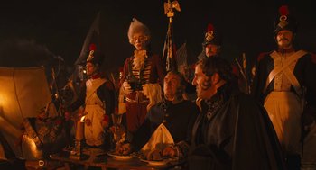Movie still from “The Brothers Grimm” (2005), directed by Terry Gilliam – A group of people sitting at a table with food; Medium shot, Over the shoulder angle