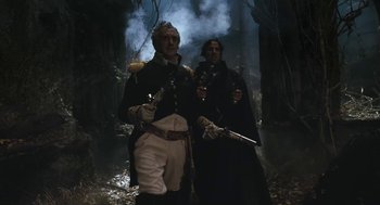 Movie still from “The Brothers Grimm” (2005), directed by Terry Gilliam – A couple of men standing next to each other holding guns; Medium shot, Low angle