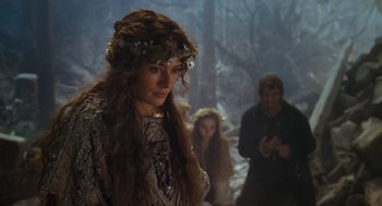 Movie still from “The Brothers Grimm” (2005), directed by Terry Gilliam – A woman with a flower in her hair in front of two other people; Medium shot, Over the shoulder angle