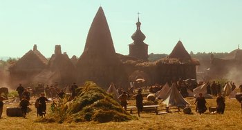 Movie still from “The Brothers Grimm” (2005), directed by Terry Gilliam – A group of people standing in front of a building; Extreme Wide shot, Low angle