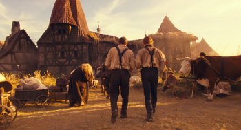 Movie still from “The Brothers Grimm” (2005), directed by Terry Gilliam – A couple of men walking across a dirt field; Wide shot, Low angle