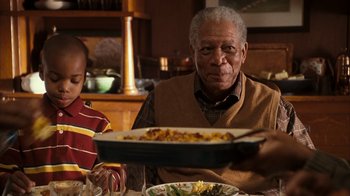 Movie still from “The Bucket List” (2007), directed by Rob Reiner – An older man sitting at a table with a plate of food; Medium shot, Over the shoulder angle